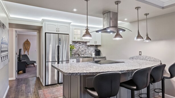 A modern kitchen with a granite countertop, stainless steel appliances, and pendant lighting.