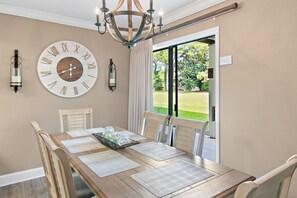 A dining room with a wooden table, two wall-mounted clocks, and a chandelier. - Seascape 22a- Hello Sunshine (Miramar Beach)