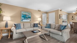 A living room with a beige sofa set, two side tables with lamps, a coffee table, and a painting on the wall. - Seascape 22a- Hello Sunshine (Miramar Beach)