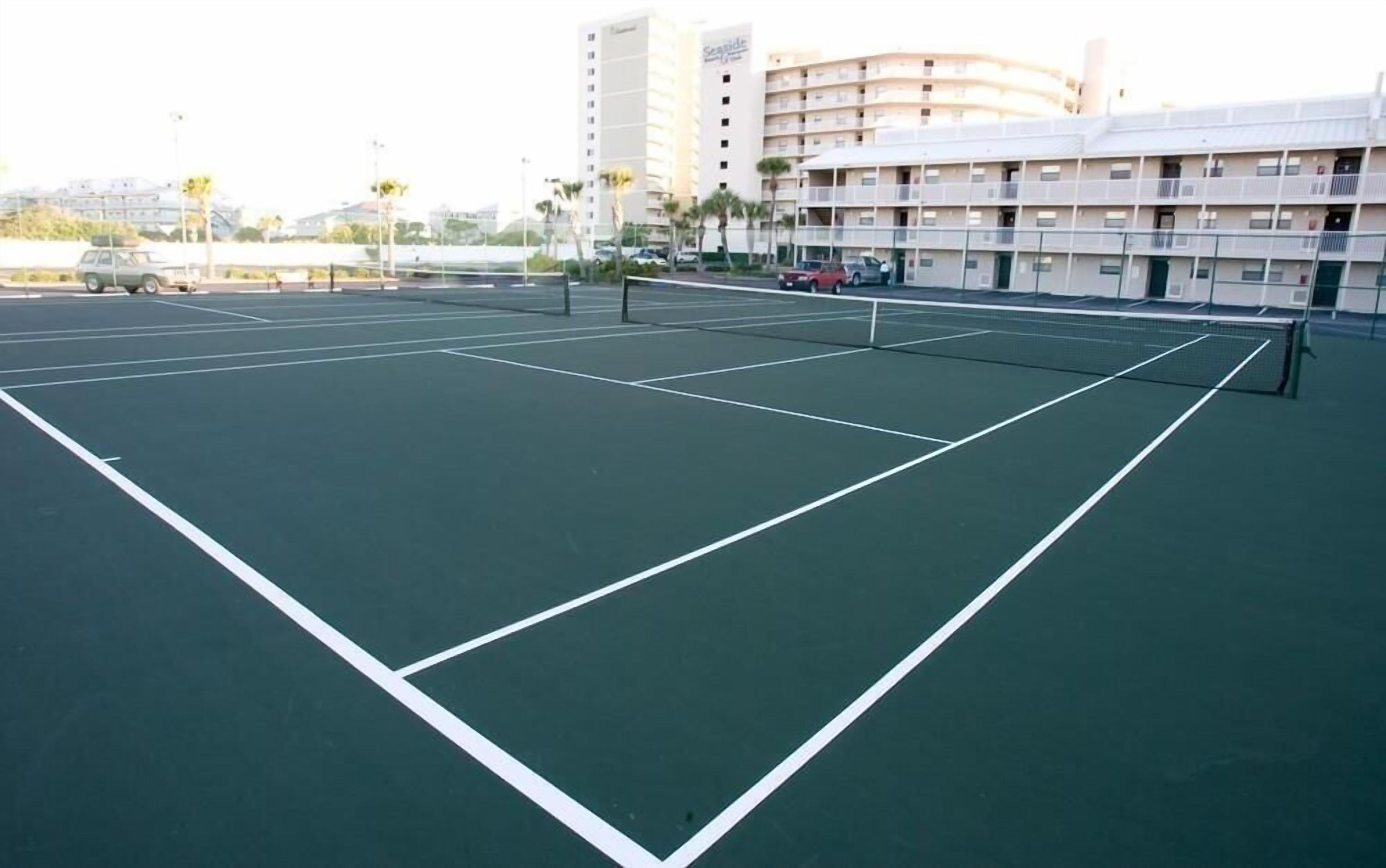 An indoor tennis court with a net, surrounded by a building with multiple balconies.
