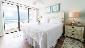 A bedroom with a large bed, a ceiling fan, a nightstand with a lamp, and a view of the ocean through a sliding door. - Seaside Beach & Racquet 3504 (Orange Beach)
