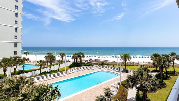 A hotel with a pool, beach view, and palm trees. - Seaside Beach & Racquet 4412 (Orange Beach)