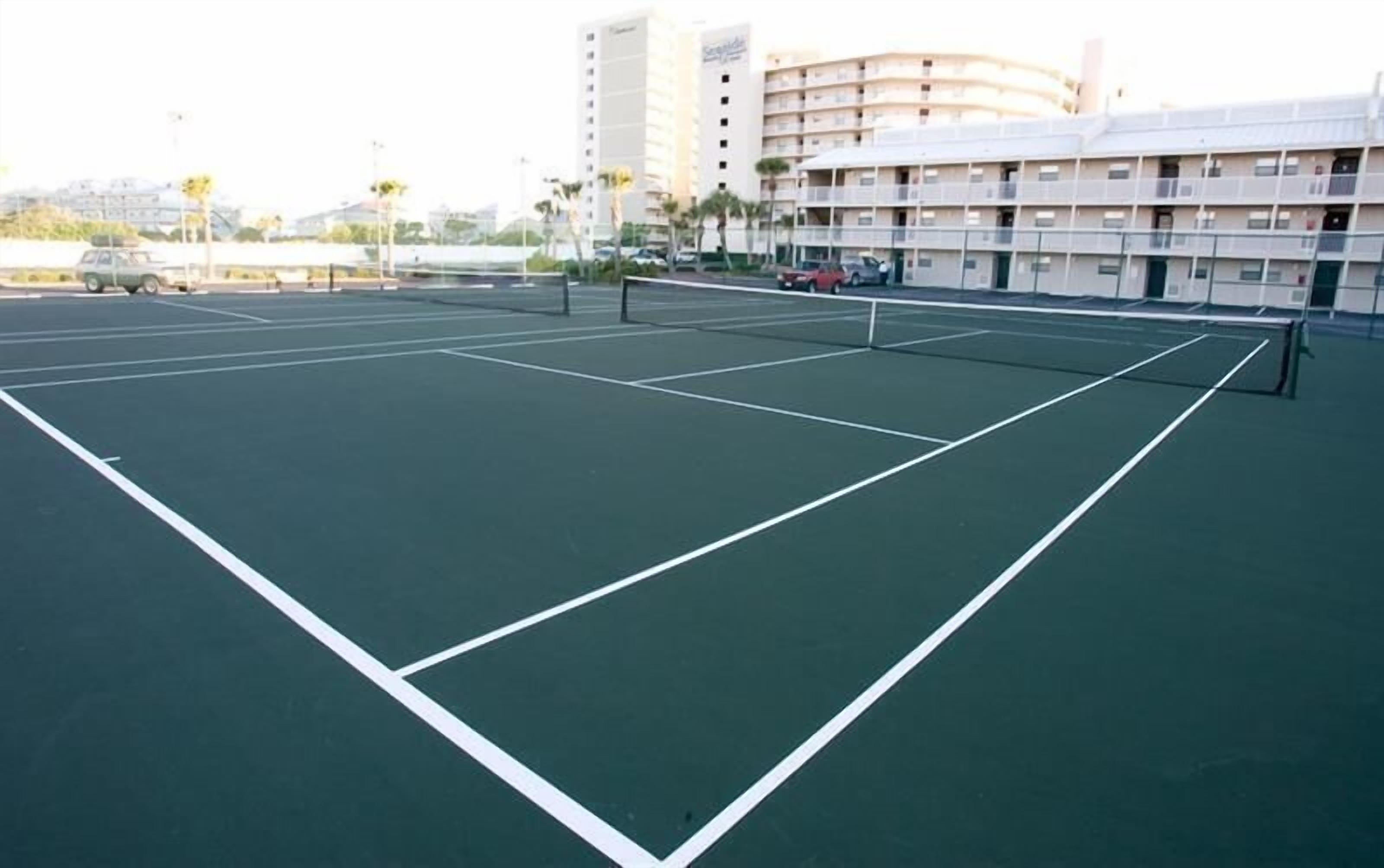 Ein Tennisplatz im Freien mit Netz, umgeben von Gebäuden.