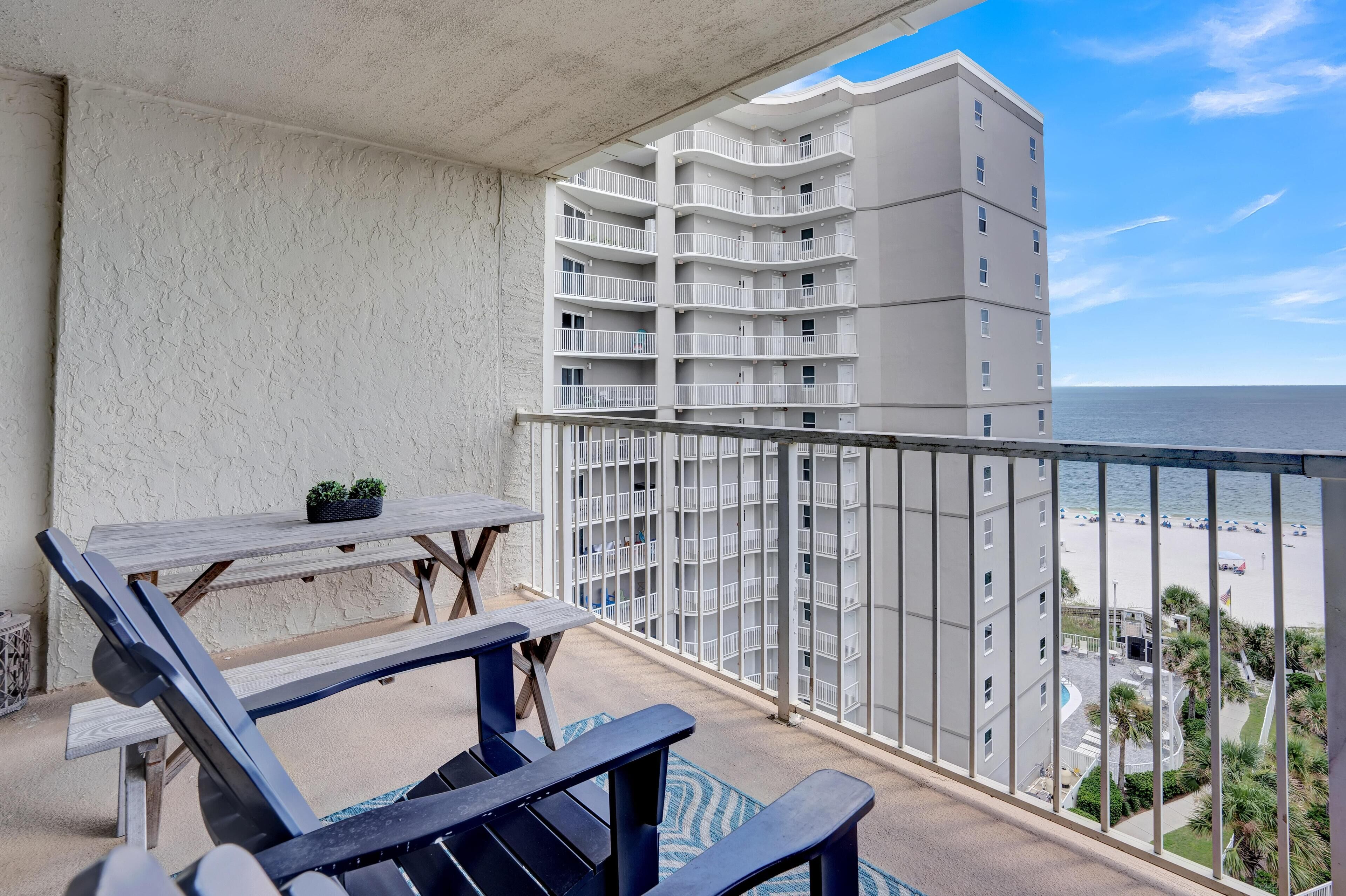 A balcony with a view of the beach and a high-rise building.