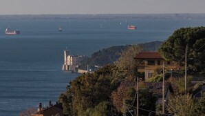 Eine Küstenansicht mit Leuchtturm, Booten und Wohnhäusern.