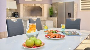 Una mesa de comedor con platos de comida, una jarra de jugo de naranja y una revista.