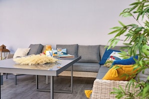 A modern living room with a grey sofa, a glass coffee table, and a wicker chair.