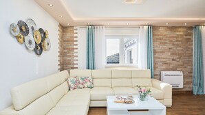 Una sala de estar moderna con un sofá seccional color beige, una mesa de centro blanca y decoración en la pared.