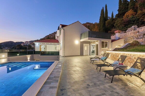 A modern pool area with lounge chairs and a stone wall.
