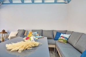 A modern living room with a grey sectional sofa, a black coffee table, and a wicker chair.
