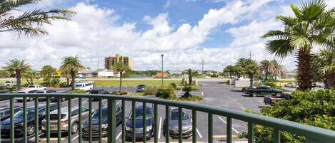 A parking lot with several cars, surrounded by palm trees and a clear sky.
