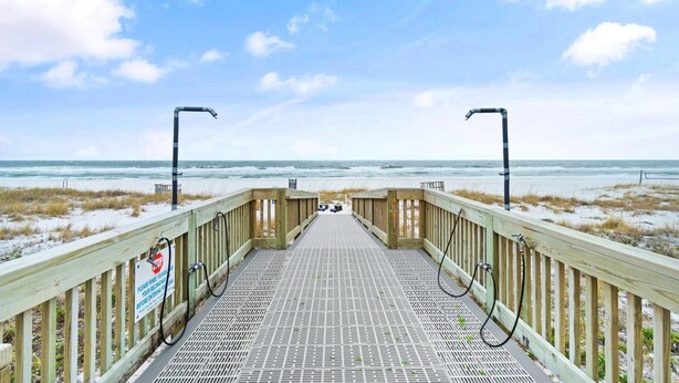 Ein Holzsteg führt zu einem Strand, ein Schild weist auf 30 Meter bis zum Wasser hin.