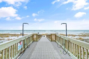 Una passerella in legno che conduce a una spiaggia, con un cartello che indica 30 metri di distanza dall'acqua.