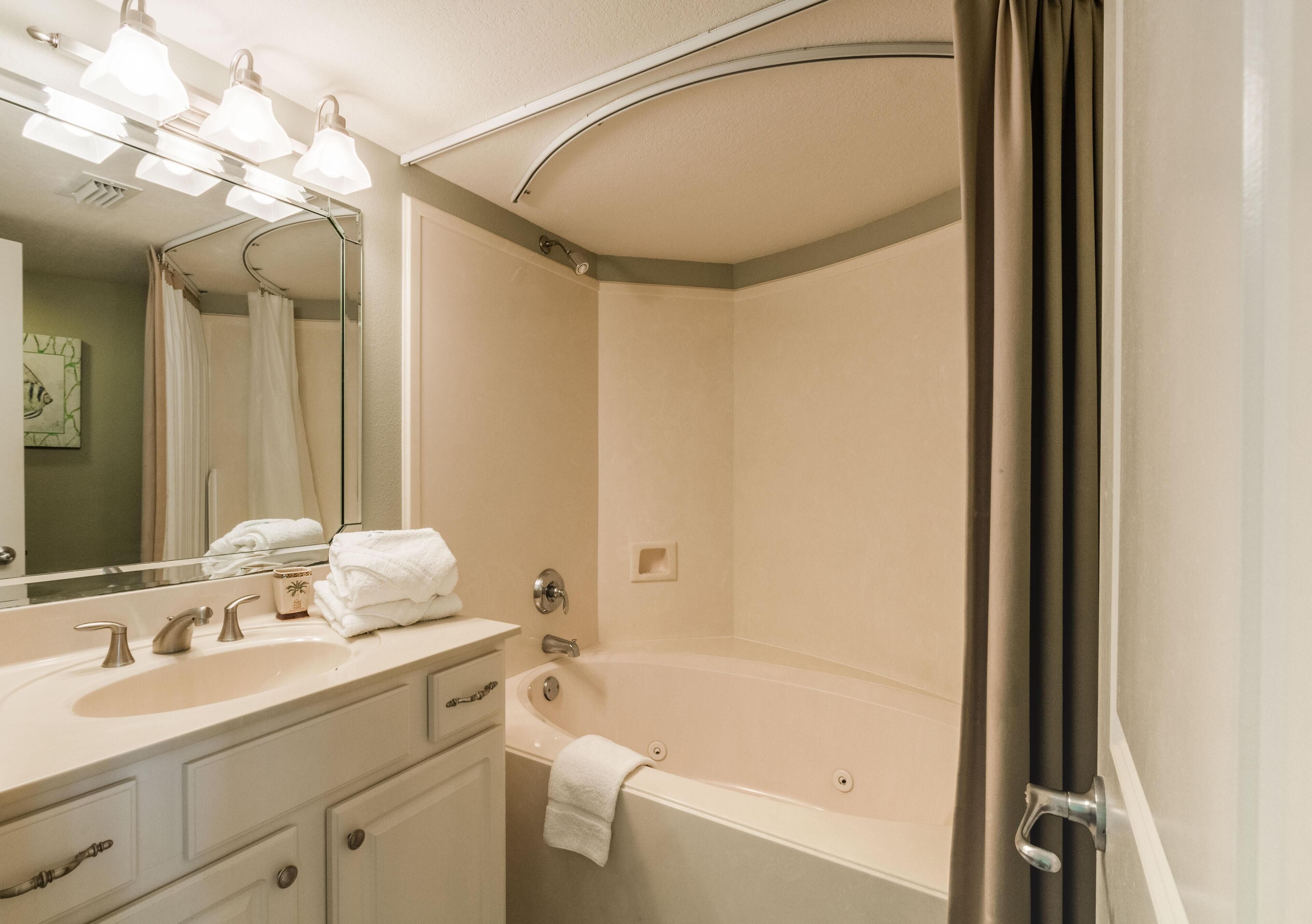 A modern bathroom with a large bathtub, a vanity with a sink, and a mirror.