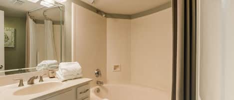 A modern bathroom with a large bathtub, a vanity with a sink, and a mirror.