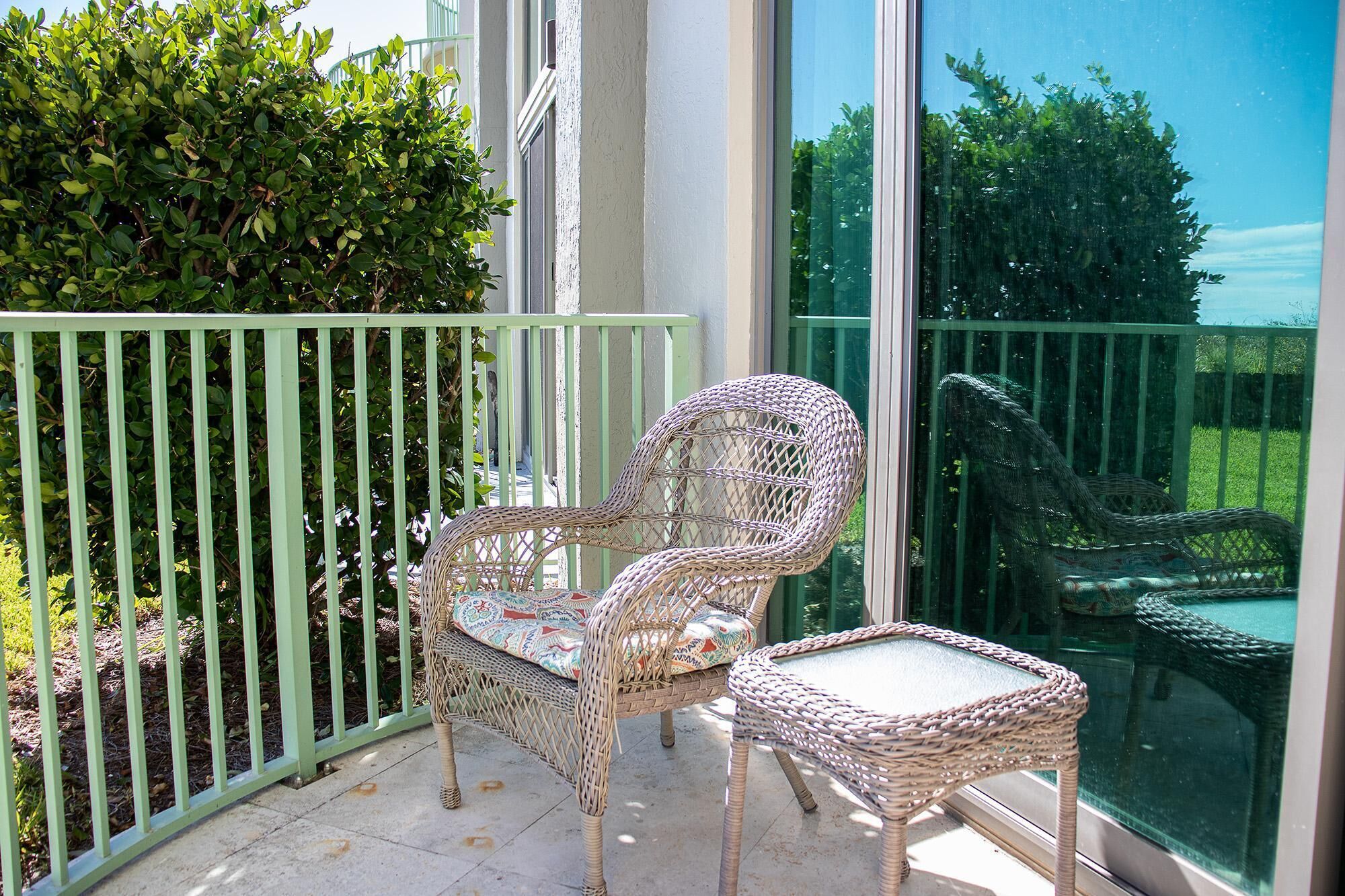 Ein Balkon mit Korbmöbeln, darunter ein Stuhl und ein kleiner Tisch.