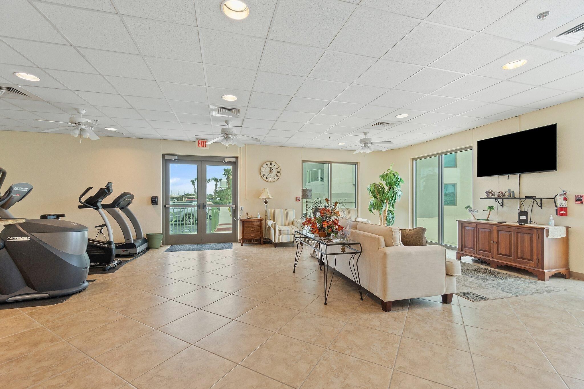 A gym with treadmills, a sofa, a TV, and a clock on the wall.