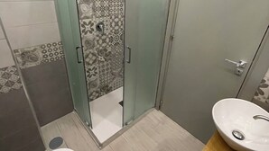 A bathroom with a shower, toilet, and sink. - Naptown Rooms (Naples)