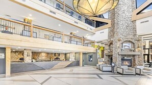 Amplio espacio interior con chimenea de piedra, varios niveles con balcones y un mostrador de recepción.