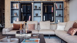 Una sala de estar moderna con un sofá, una mesita de centro y estanterías empotradas con libros y objetos decorativos.