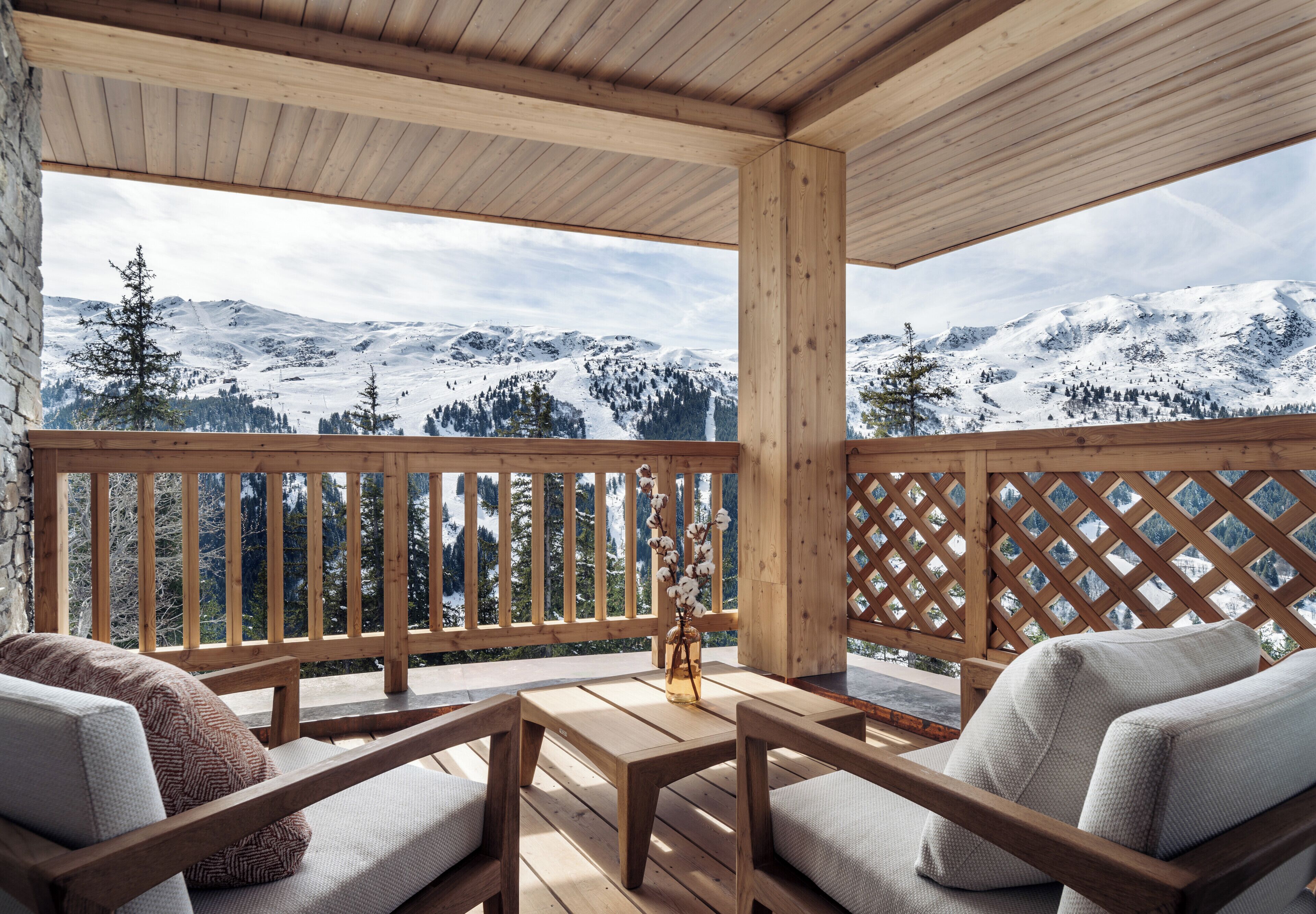 Una terraza de madera con una mesa y sillas, con vistas a un paisaje montañoso nevado.