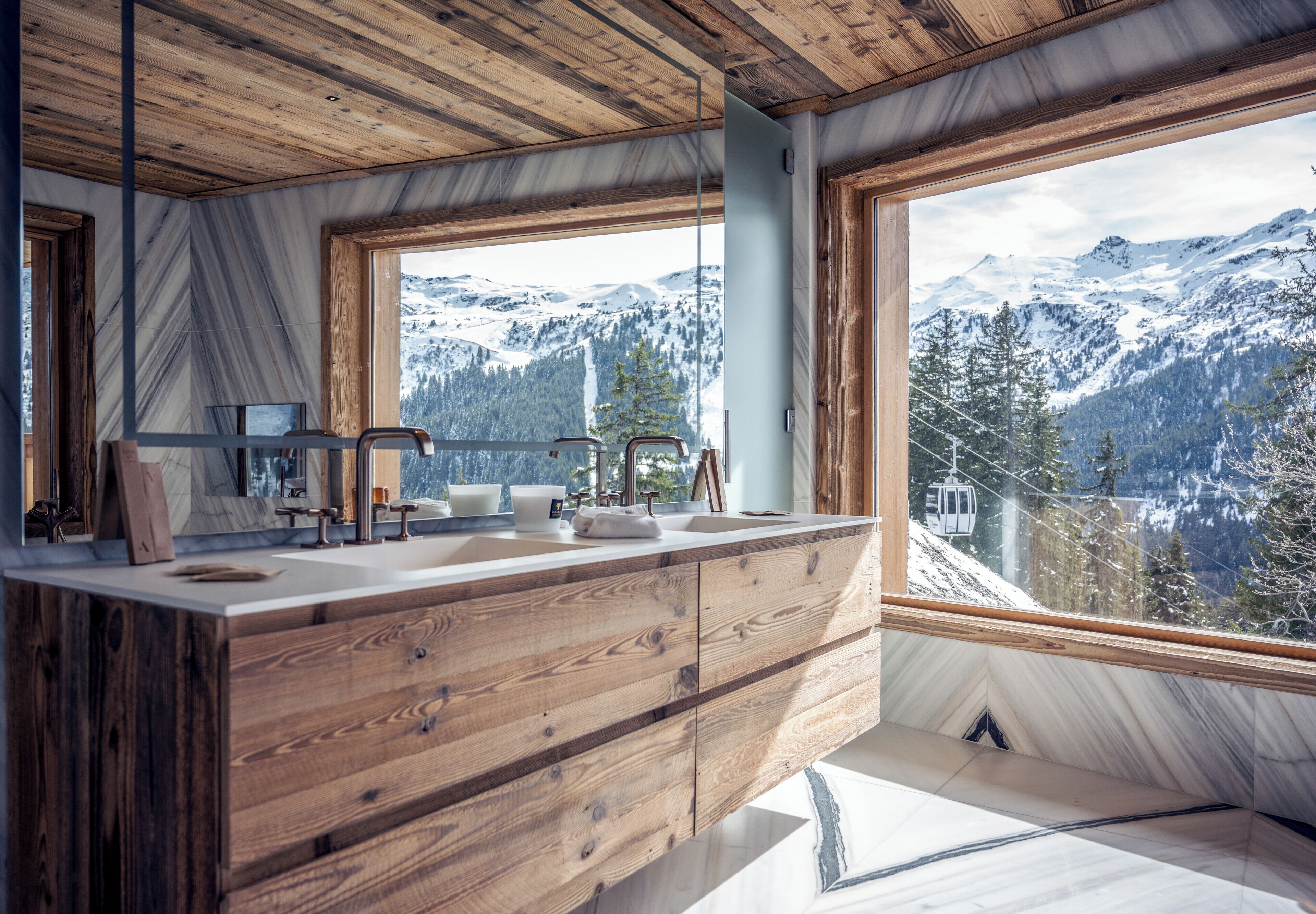 Une salle de bain moderne avec des meubles en bois et une grande fenêtre donnant sur un paysage de montagnes enneigées.