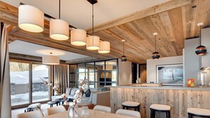 A modern kitchen with wooden accents, a bar area, and a dining space with a large table and bar stools.
