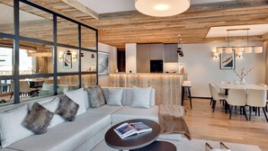 A modern living room with a large sectional sofa, a round coffee table, and a dining area with a table and chairs.