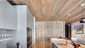 Una cocina moderna con detalles de madera, encimera de mármol y horno empotrado.