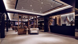 Ein modernes Interieur mit Holzboden, einer Rezeption und einer Sitzecke mit Stuhl und kleinem Tisch.