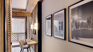 Un pasillo con vigas de madera en el techo, un comedor con mesa y sillas, y obras de arte enmarcadas en las paredes.