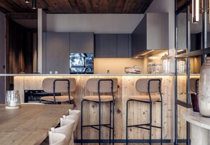 Eine moderne Küche mit Holzelementen, Barhocker und einem Esstisch.