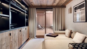 A modern living room with a wooden ceiling, a large flat-screen TV, a beige sofa, and a framed picture on the wall.