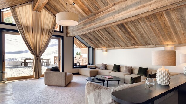 A modern living room with a wooden ceiling, large windows, a sofa set, and a coffee table.