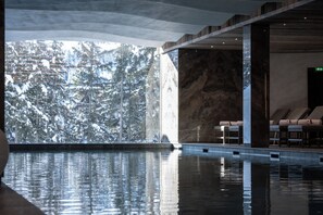 Una piscina interior con vistas claras a árboles cubiertos de nieve.