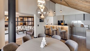 A modern kitchen with a central island, bar stools, and a dining area with a round table and chairs.