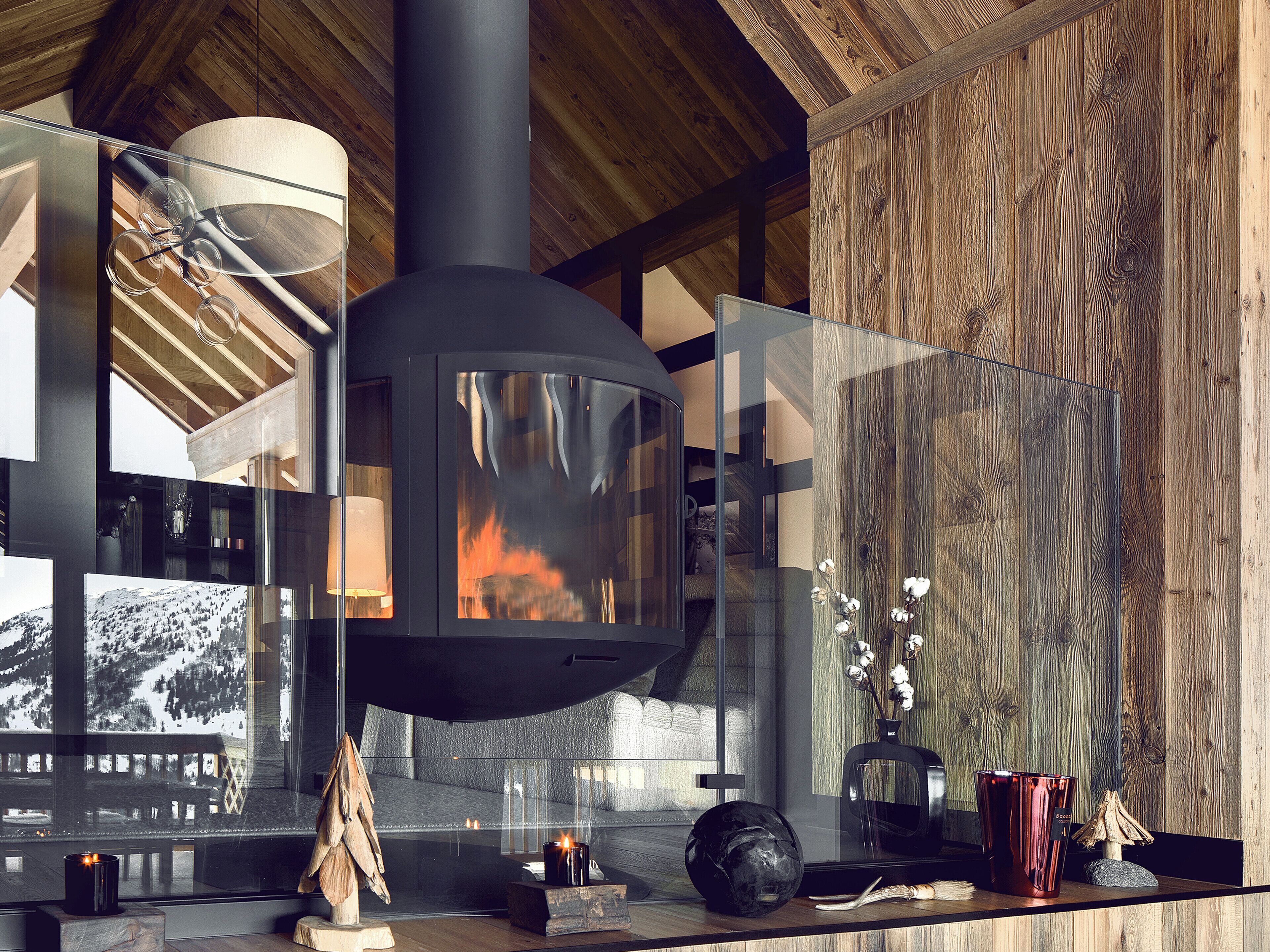 A modern interior with a glass fireplace, wooden beams, and a view of a snowy landscape.