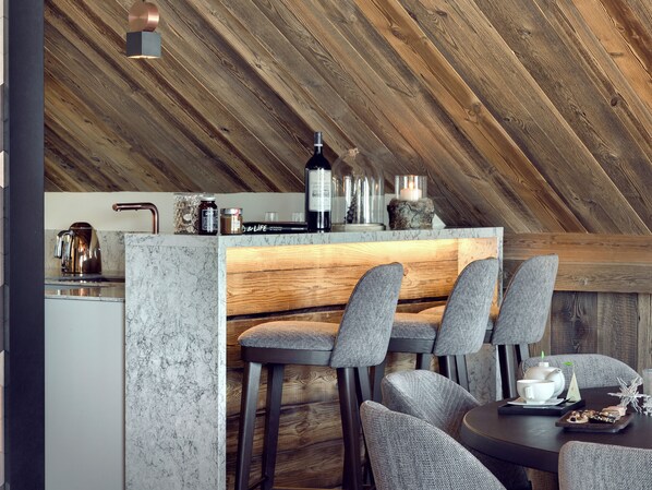 Una cocina moderna con techo de madera, encimera de mármol y taburetes de bar.