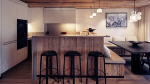 Una cocina moderna con una isla de madera, taburetes y lámparas colgantes.