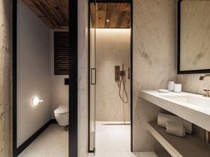 Ein modernes Badezimmer mit einer gläsernen Duschkabine, einer weißen Toilette und einem Marmor-Waschtisch mit Spüle und Handtuchschrank.