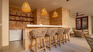 A kitchen with a bar area, wicker chairs, and a ceiling fan. - Casa Los Dichos (Puerto Escondido)