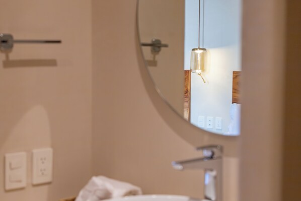 A bathroom with a round mirror, a towel rack, and a light fixture. - Casa Los Dichos (Puerto Escondido)
