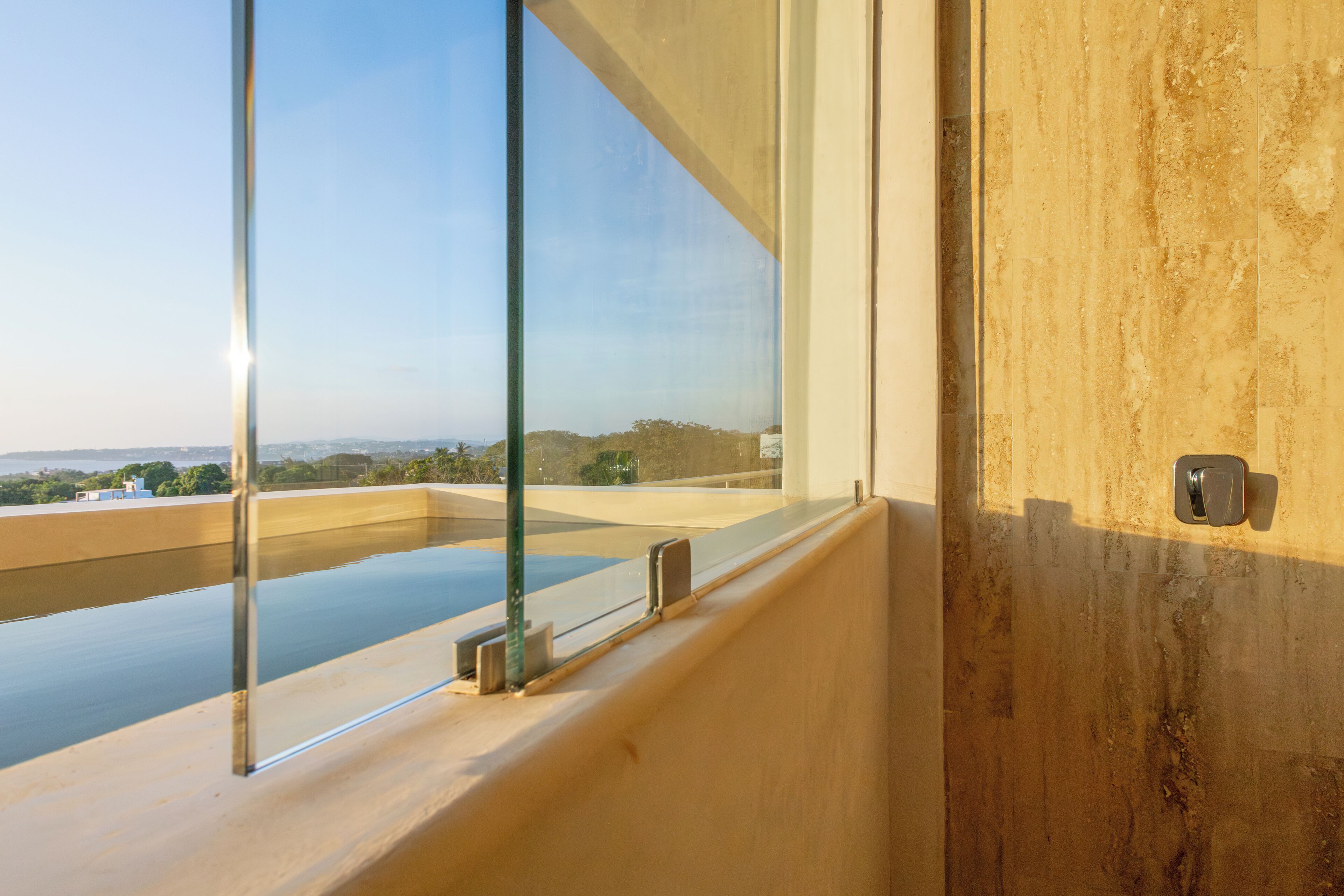 A modern interior with a large window overlooking a pool and distant landscape.