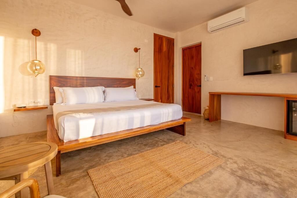 A bedroom with a wooden bed, a small table, a TV, and a door.