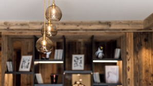 Un interior de madera con una lámpara colgante y estantes que exhiben cuadros enmarcados y objetos decorativos.