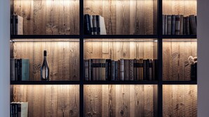Una estantería con varios estantes, cada uno con libros y una botella.