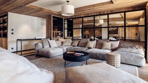 Una sala de estar moderna con un sofá modular, una mesa de centro redonda y un gran ventanal con marcos de madera.