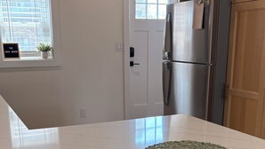 A kitchen with a white countertop, stainless steel appliances, wooden cabinets, and wicker bar stools.