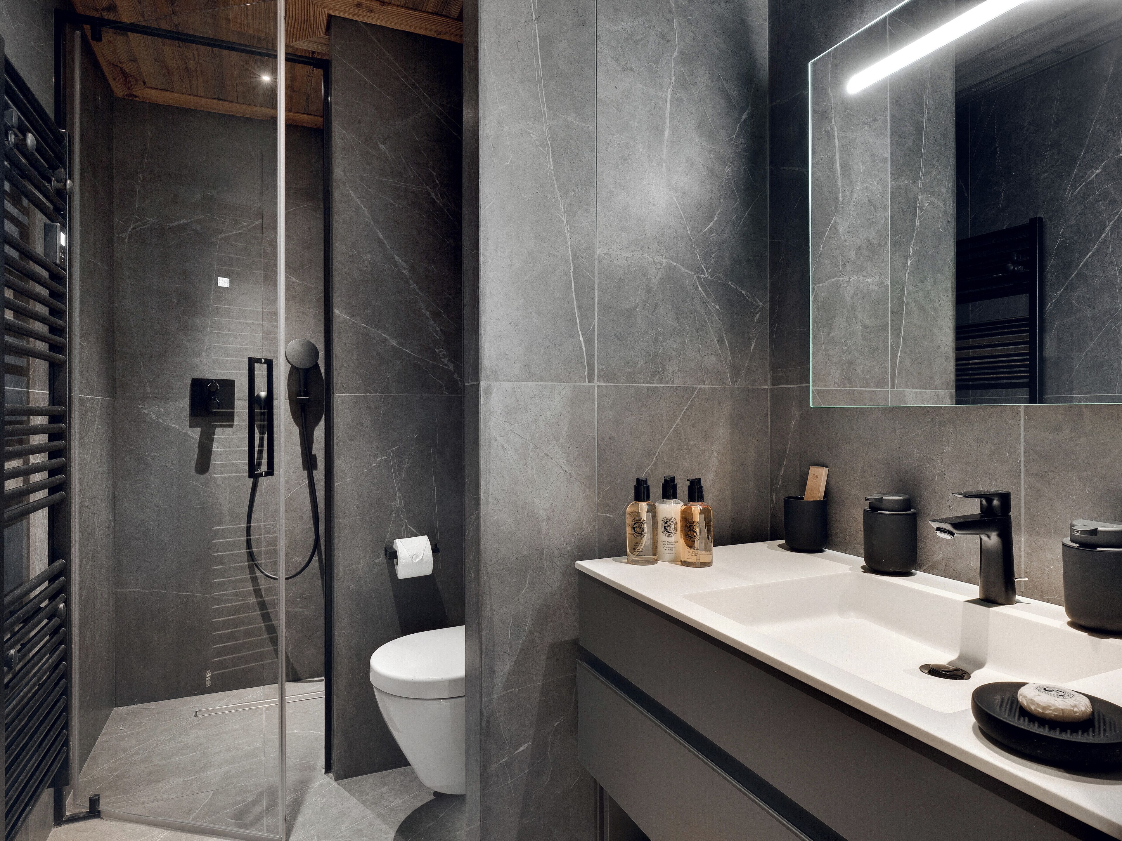 Un baño moderno con ducha, inodoro y tocador con artículos de aseo.