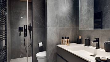 Un baño moderno con ducha, inodoro y tocador con artículos de aseo.